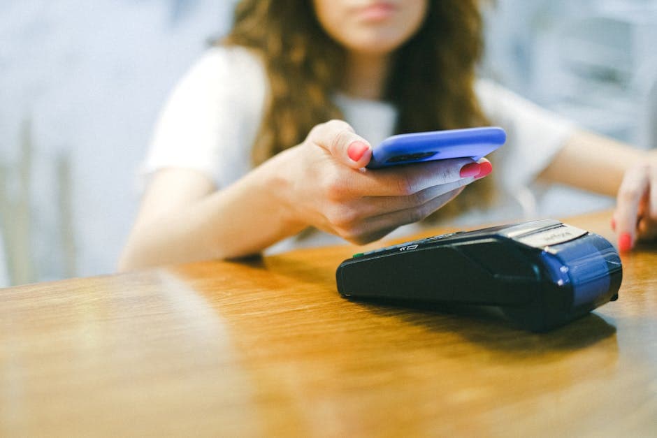 Customer paying by mobile money with a smartphone at a shop counter