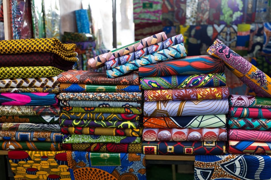 Stacks of colourful African wax-print fabrics at a market in Cotonou